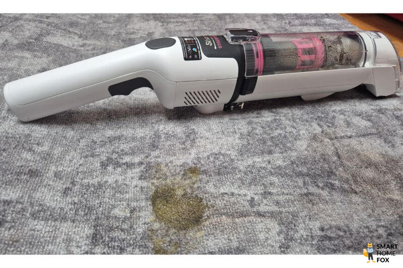 Der Shark Stainforce Akku-Fleckenreiniger liegt auf dem Teppich in Benutzung, man sieht das Handgerät.